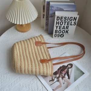 Close-up of dual-tone straw woven tote bag featuring beige stripes and leather handles