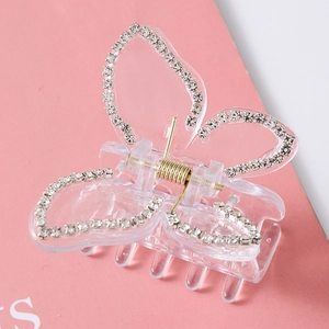 Detail of butterfly hair claw clip with white rhinestones and golden spring on pink base