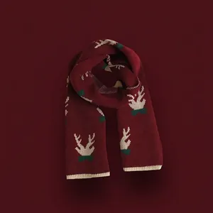 Detail of red Christmas knit scarf with white reindeer horn patterns and green accents