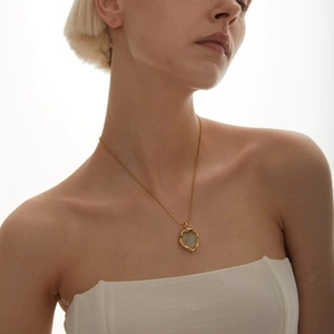 Detailed view of an 18k gold plated brass necklace with a vintage coin pendant and lava texture
