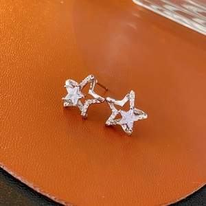 Macro shot of silver star stud earrings with sparkling cubic zirconia on orange leather