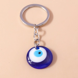 Detailed close-up of blue Greek Evil Eye charm with silver keychain on soft beige background