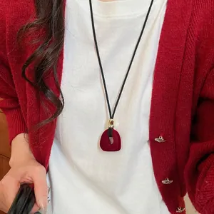 Vintage red flocked resin pendant necklace on black cord styled with red knitwear