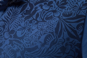 Close-up of blue polo shirt fabric with detailed botanical print and breathable mesh texture
