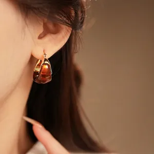 Vintage gold plated earrings with amber resin drop on model under soft warm light