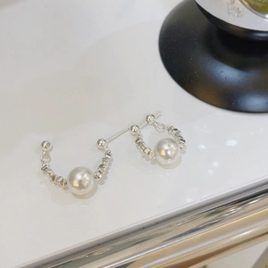 Detail of silver beaded hoop earrings with a central white pearl and a minimalist design