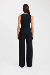 Back view of a woman in a black sleeveless vest and wide-leg trousers set with smooth fabric