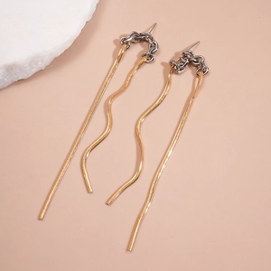 Detail shot of bicolor gold and silver chain tassel earrings on a warm beige background