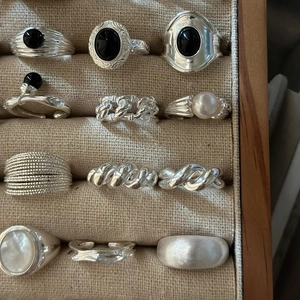 Close-up of various S925 sterling silver rings with black gemstones and pearls in a jewelry box