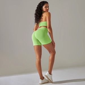 Detail of neon green seamless yoga set with high waist shorts and crop top on model