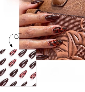 Macro detail of glossy tortoiseshell and dark brown stiletto press-on nails on leather