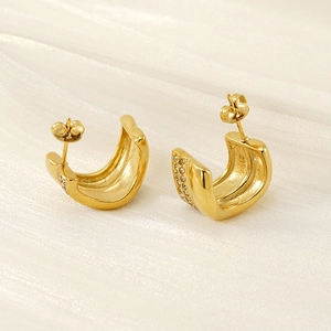 Elegant C-shaped gold plated earrings with double row cubic zirconia on silk background