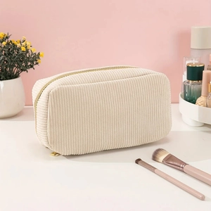 Detail of beige corduroy toiletry bag with golden zipper on a clean white vanity table