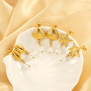 Golden sea shell and starfish earrings set with pearls on elegant silk background
