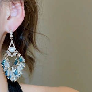 Detail of luxury drop earrings featuring white pearls and blue crystal beaded tassels