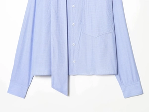 Detail of light blue cropped shirt showing fine fabric texture and front pocket