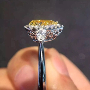 Macro detail of pear cut yellow zircon ring with halo diamonds and ornate silver band