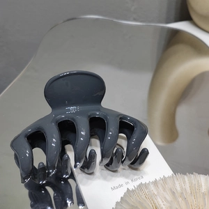 Detailed view of glossy dark gray hair claw clip on a reflective mirror surface