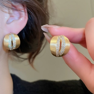 Macro detail of 18K gold C-shaped earrings featuring brushed metal and pavé zircon stones