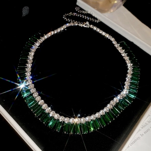 Close-up of emerald green rectangle gems and round crystals in luxury jewelry box