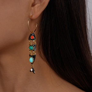 Detail of vintage fish-shaped hoop earring with colorful stones on model