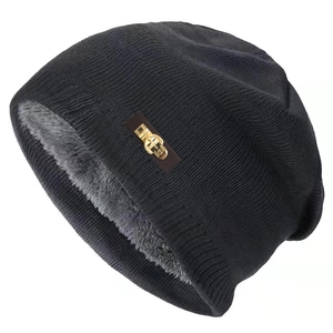 Détail du bonnet en maille noir avec doublure polaire grise et boucle en cuir métallique