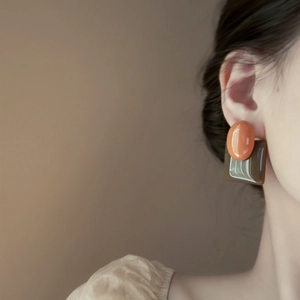 Detail of vintage geometric earrings with orange oval and brown resin square on model