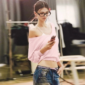 Detail of pink off-shoulder long-sleeve knit top paired with dark blue denim jeans