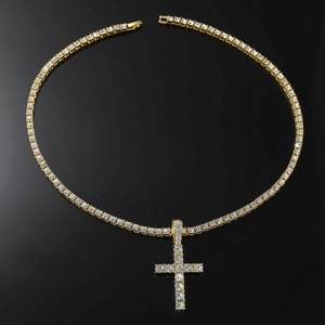 Macro detail of iced-out gold cross pendant and matching tennis chain on black background