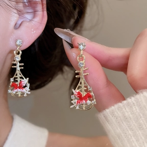 Close-up of golden pipa-shaped earrings with red horse pattern and shiny rhinestones