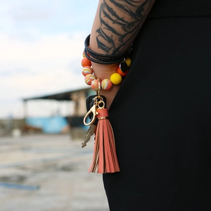 Close-up of silicone beaded wristlet keychain in yellow and orange on a tattooed wrist