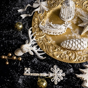 White glitter Christmas ornaments including deer, stars and cones on a golden platter