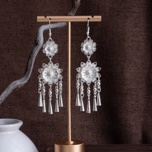Dettaglio di orecchini etnici in argento con motivi floreali e nappe coniche