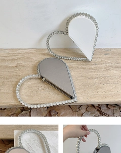 Detail view of heart-shaped clutch bag showing rhinestone handle and zip closure