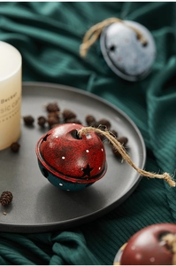 Detail of red and blue vintage metal Christmas bell with star cutouts and hemp rope hanging
