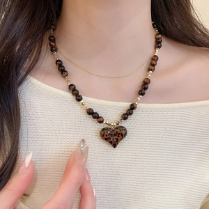 Macro view of leopard print heart pendant on beaded 18K gold plated layering necklace