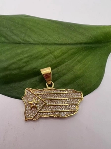 Macro detail of gold-plated Puerto Rico map pendant with sparkling crystals on green leaf