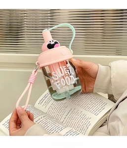 Pink and cyan cute monster straw cup with woven strap shown in a lifestyle setting