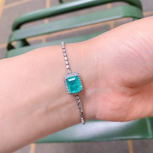 Close-up of a silver bracelet with a rectangular green zircon stone on a woman's wrist