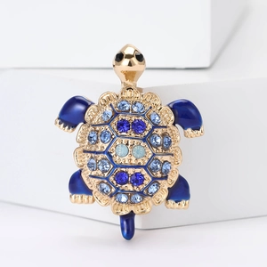 Macro shot of gold turtle brooch featuring blue rhinestones and blue enamel inlay detail