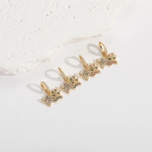 Close-up of golden animal pendants with colorful rhinestones on white rock background