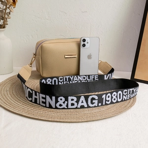 Chic beige crossbody camera bag with trendy patterned wide strap and a metal plaque