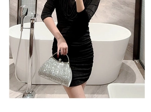 Detailed shot of silver glitter evening clutch bag with metal handle and rhinestone clasp