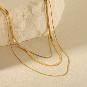 Three-layer 18K gold plated stainless steel snake chain necklace on stone background