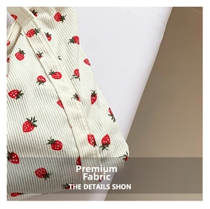 Close-up of white corduroy fabric with strawberry print showing soft vertical texture