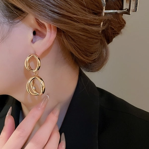 Primo piano dettagliato di orecchini minimalisti in oro a doppio ovale su una modella
