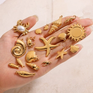 Detailansicht goldener Meeresanhänger wie Seestern und Krabbe in der Hand für den Maßstab