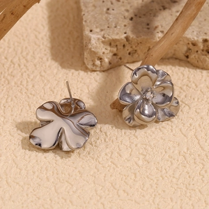 Macro detail of silver floral stud earrings featuring a five-petal design and zircon center