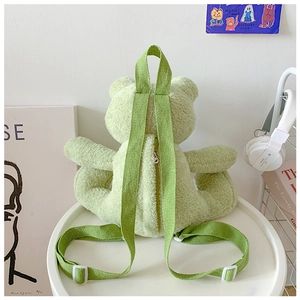Detail of light green plush frog backpack with zipper closure and soft canvas straps