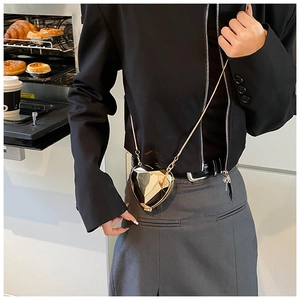 Sac à bandoulière doré en forme de cœur avec facettes géométriques porté par un modèle